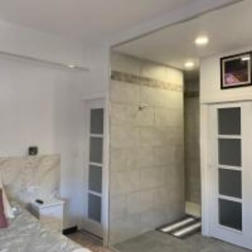 Baño moderno con ducha a ras de suelo, azulejos blancos y iluminación empotrada en apartamento de Santa Cruz de Tenerife