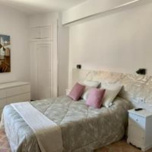 Dormitorio luminoso en apartamento de Santa Cruz de Tenerife con cama de matrimonio, almohadas rosas, mesitas blancas y vistas a la ciudad