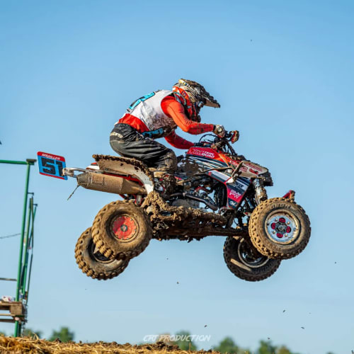 Pilote de VTT effectuant un saut acrobatique sur piste boueuse près de Gorrevod, France