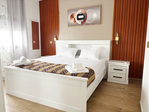 Modern bedroom at DakarByDays apartment with white bed, gold patterned runner, red curtains, and contemporary wall art in