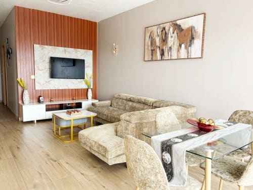 Modern Dakar apartment living room with beige sectional sofa, wooden TV wall, and yellow-framed coffee table