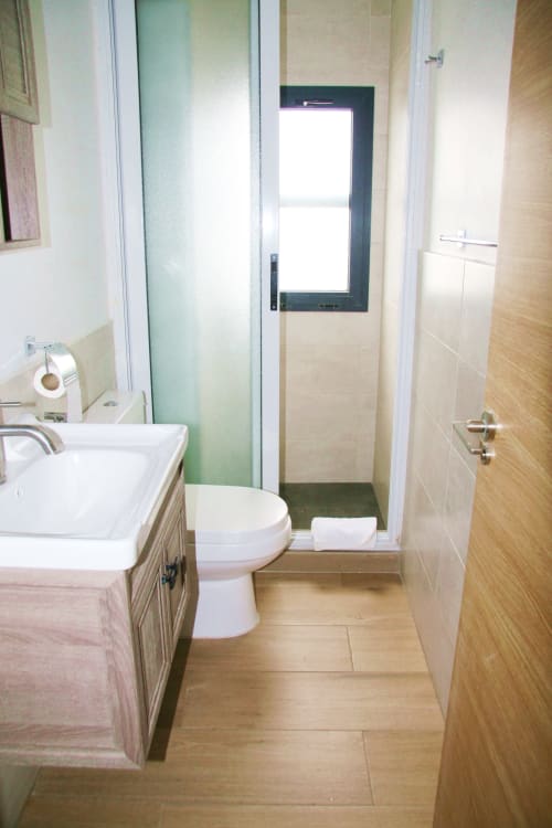 Modern bathroom in DBD703 apartment at DakarByDays Dakar with sink, toilet, shower and wood-tiled flooring