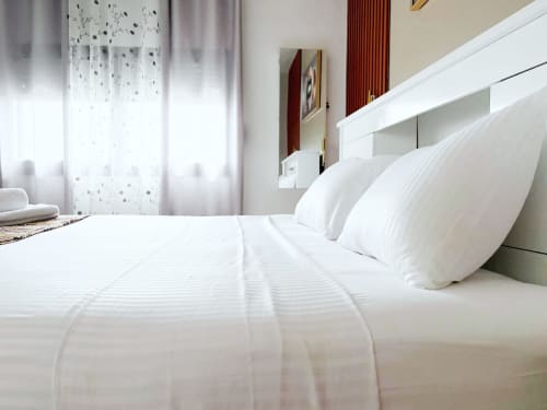 Clean white bedroom with pillows and striped bedding at DakarByDays apartment in Dakar, Senegal