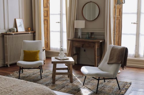 Elegant seating area at Trama en Perche B&B in Mortagne-au-Perche with cream chairs, wooden desk, and round mirror.