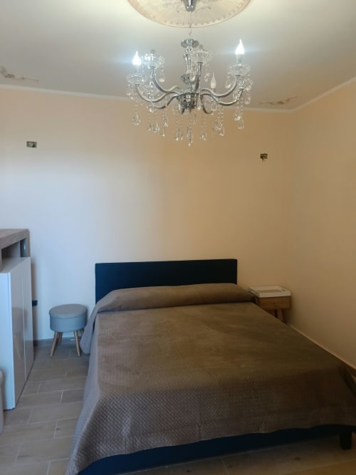 Camera doppia Atena Smartrooms a Sellia con letto blu scuro, lampadario in cristallo e arredi moderni