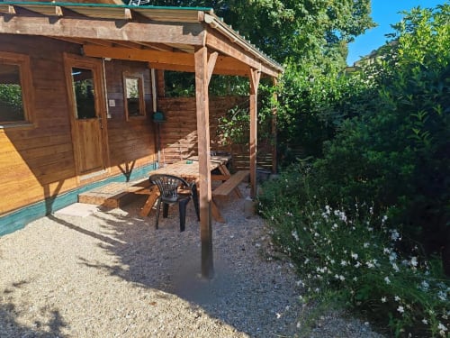 Terrasse du jardin Le Verger avec pergola en bois, salon de détente et verdure luxuriante aux Gites De Petrocoriis, Boulazac