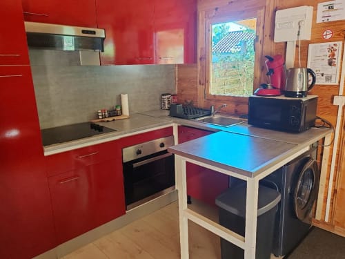 Cuisine rouge moderne du gîte Le Verger aux Gites De Petrocoriis à Boulazac, équipée d'appareils inox et vue sur le jardin