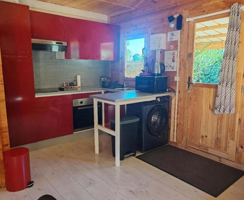 Cuisine moderne et buanderie du gîte Le Verger aux Gîtes De Petrocoriis, Boulazac, avec meubles rouges et bois