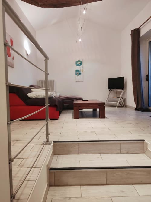Chambre studio moderne aux Gîtes De Petrocoriis à Boulazac avec lit rouge, mobilier en bois et télévision