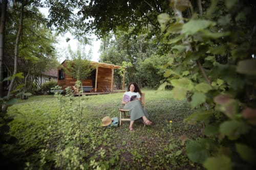 Vrouw leest in een tuinstoel op het Domaine de Blanvatel landgoed in Saint-Pierre-en-Auge, omringd door groen en hagen