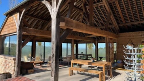 Ruim villa eet- en loungegedeelte in Domaine de Blanvatel met houten balken, grote ramen met uitzicht op de tuin