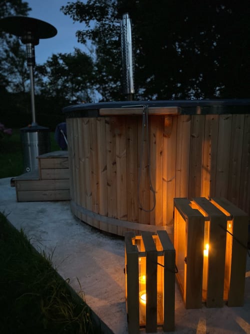 Verlichte houten hottub in de schemering met trappen bij Domaine de Blanvatel, een Franse villa met tuinuitzicht