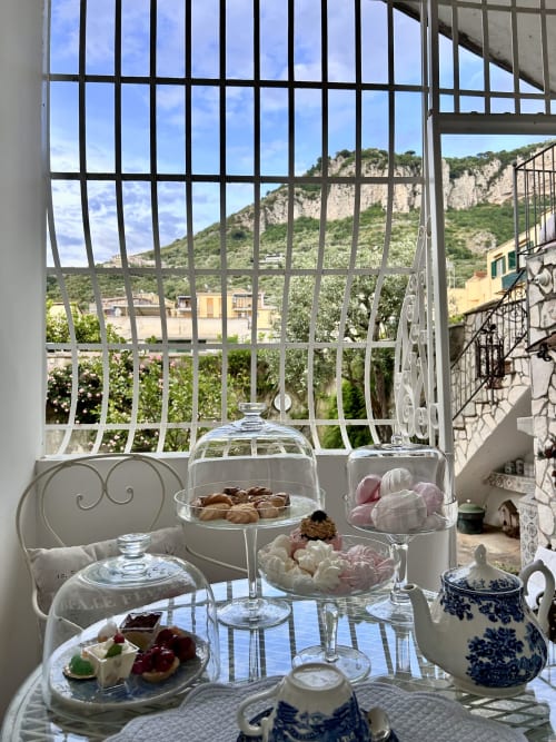 Elegante colazione al Relais Palazzo Cacace con pasticcini, dolcetti e teiera in ceramica blu con vista su Meta di