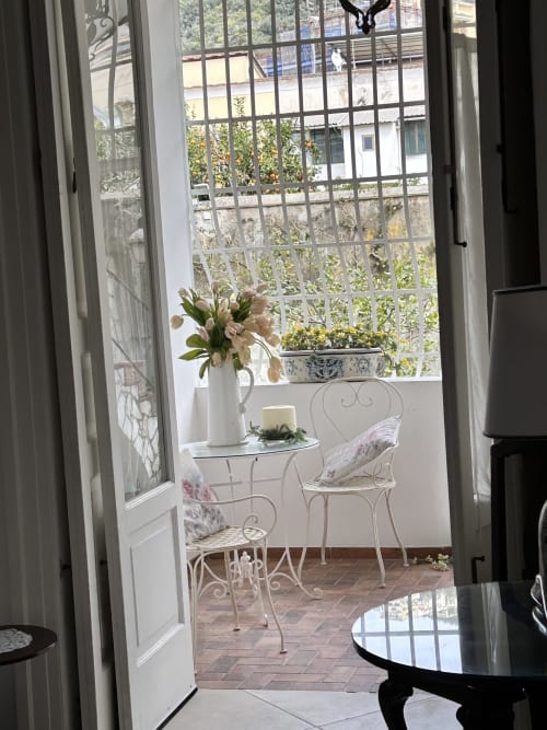 Elegante balcone con vista sul giardino di Relais Palazzo Cacace, Meta di Sorrento, con mobili in ferro battuto e brocca bianca