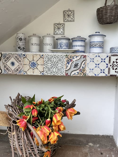Ripiano decorativo rustico al Relais Palazzo Cacace con barattoli di ceramica blu e bianco, piastrelle decorate e vivaci tonalità rosso-giallo