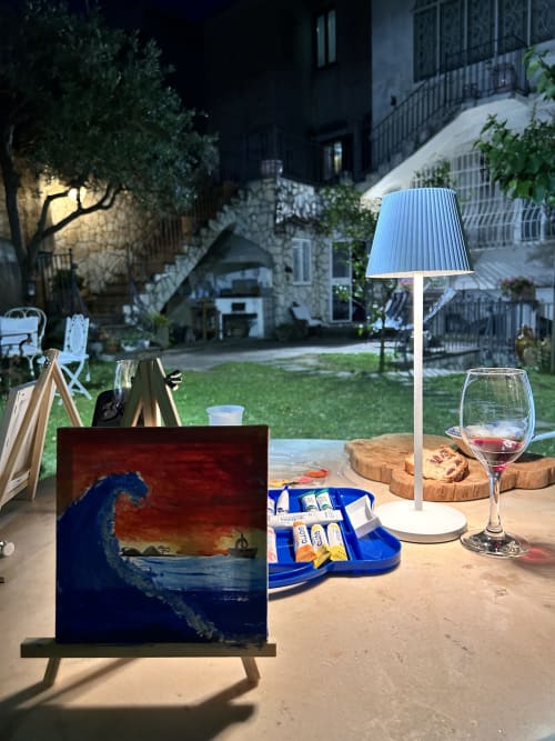 Allestimento serale nel giardino di Relais Palazzo Cacace con vino, opere d'arte e lampada blu a Meta di Sorrento