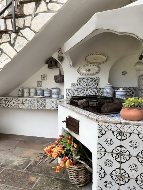 Affascinante angolo cottura della camera Daphne al Relais Palazzo Cacace, Meta di Sorrento, con piastrelle azzurre decorate, stoviglie in ceramica