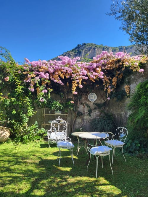 Affascinante area lounge nel giardino del Relais Palazzo Cacace a Meta di Sorrento con pergolato di buganvillea fiorita e ferro battuto