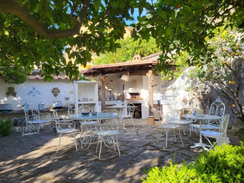 Affascinante terrazza in giardino presso Relais Palazzo Cacace a Meta di Sorrento con mobili in ferro battuto bianco e rigogliosa vegetazione