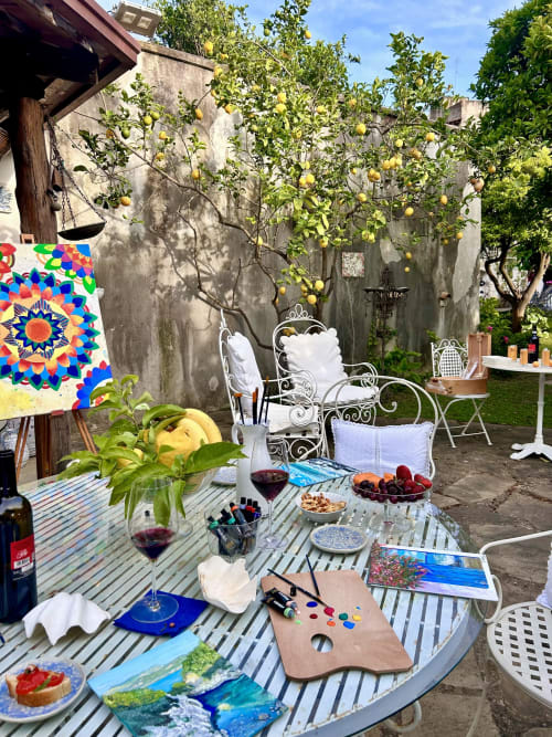 Cortile giardino del Relais Palazzo Cacace a Meta di Sorrento con limoni, tavolo all'aperto, vino, materiali artistici