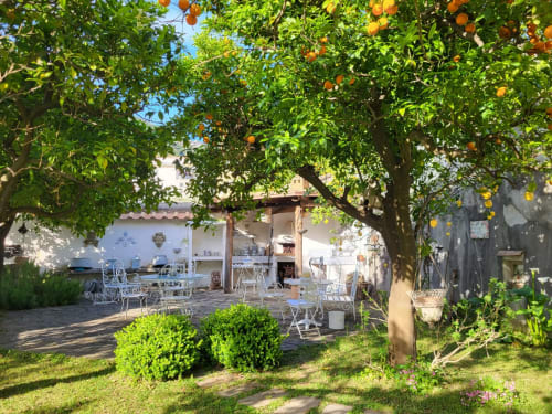 Aranci ombreggiano la terrazza del Relais Palazzo Cacace a Meta di Sorrento, con mobili bianchi e vista sul giardino