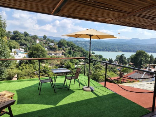 Terraza de Casa Acento en Valle de Bravo con vistas al lago, sombrilla, asientos y paisaje de montaña