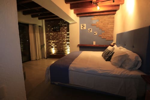Habitación Magnolia en CASA ACENTO, Valle de Bravo: cama moderna, muros de ladrillo expuesto, vigas de madera e iluminación ambiental