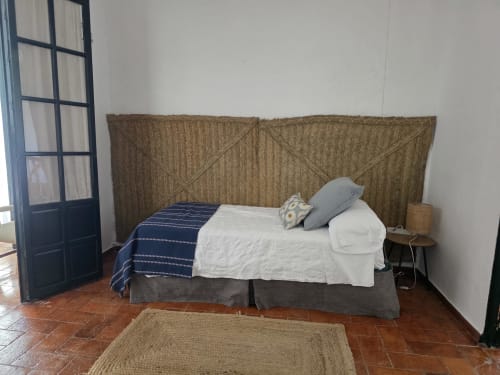 Dormitorio en Hacienda Las Lumbreras, Montellano: cabecero tejido, ropa de cama blanca y pisos de terracota