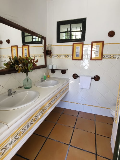 Baño rústico de Hacienda Las Lumbreras con dobles lavabos, piso de barro, y obra de arte enmarcada