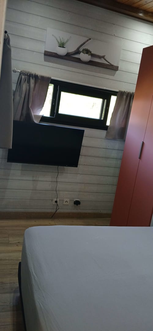 Chambre moderne du Chalet Eléonore au Domaine de Jade avec TV murale, étagère bois décorative et vue montagne