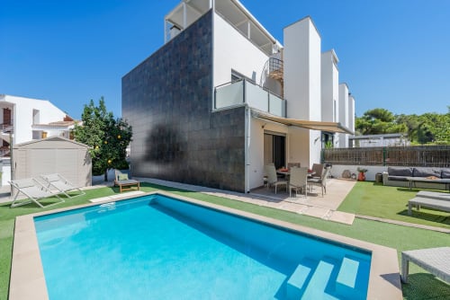 Villa moderna en Alcudia con piscina privada, terraza, zona de descanso y jardín cuidado bajo cielo azul
