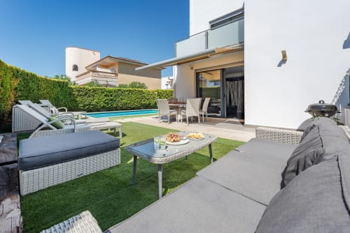 Luxury villa patio in Alcudia with private pool, lounge seating, dining area, and manicured garden
