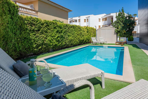 Private pool villa in Alcudia with turquoise swimming pool, lounge chairs, manicured lawn, and white villas nearby
