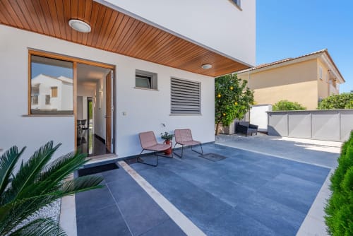 Modern villa terrace in Alcudia with blue stone patio, lounge chairs, and garden views at MallorcaWeek