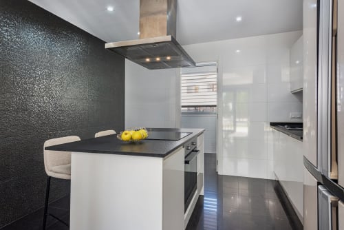 Modern kitchen in MallorcaWeek villa Acacias, Alcudia with black textured backsplash, white cabinetry, island seating, and
