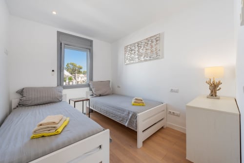 Modern twin bedroom in ACACIAS villa, Alcudia with white beds, wooden floors, and window overlooking garden views