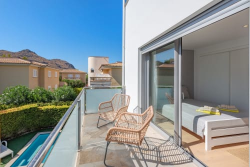 Bright terrace with wicker chairs overlooking pool and garden at Acacias villa in Alcudia