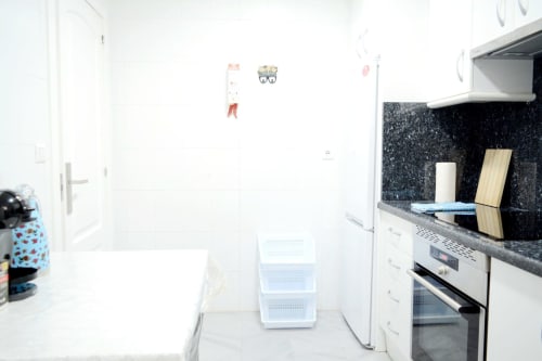 Cocina moderna del apartamento Royal Banus en Marbella con gabinetes blancos, encimera de granito negro y electrodomésticos empotrados