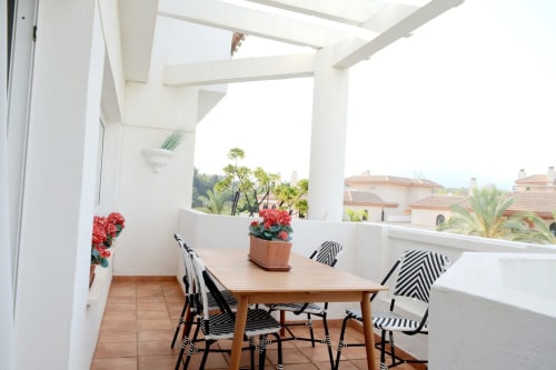 Terraza frente al mar del apartamento Royal Banus en Marbella con mesa de comedor, sillas a rayas y vistas a las montañas