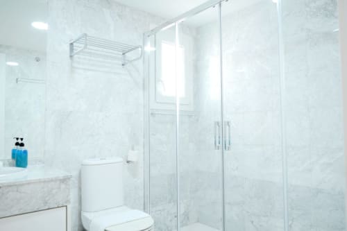 Baño moderno en mármol con ducha de cristal en el apartamento Royal Banus de Marbella