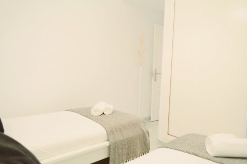 Dormitorio minimalista del apartamento Royal Banus en Marbella con camas gemelas, toallas enrolladas y decoración moderna