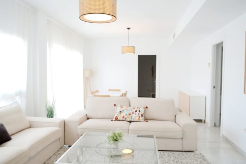 Luminoso y moderno salón del apartamento Royal Banus Marbella con sofás color crema, mesa de cristal e iluminación natural
