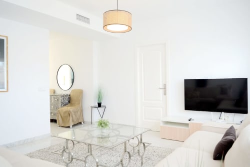 Salón moderno del apartamento Royal Banus en Marbella con televisor de pantalla plana, mesa de cristal y mobiliario contemporáneo