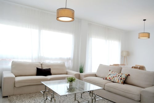 Salón luminoso en Royal Banus, Marbella con sofás beige, mesa de cristal y amplias ventanas con vistas a las montañas