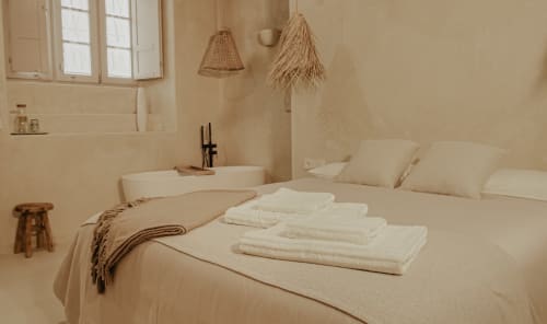 Chambre andalouse minimaliste avec linge blanc, luminaires suspendus tissés et lavabo à EntreArcos Casa Eco-Boutique
