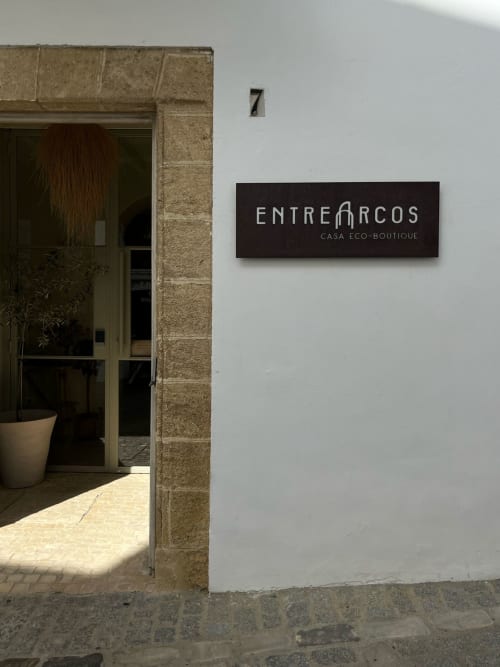 Entrée de l'EntreArcos Casa Eco-Boutique à Vejer de la Frontera, numéro 7 avec enseigne noire sur mur blanc