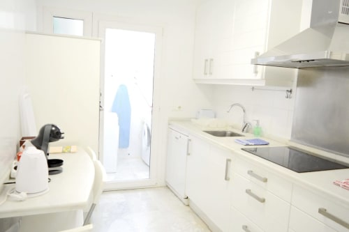 Modern white kitchen with stainless steel appliances at Royal Banus beachfront apartment in Marbella
