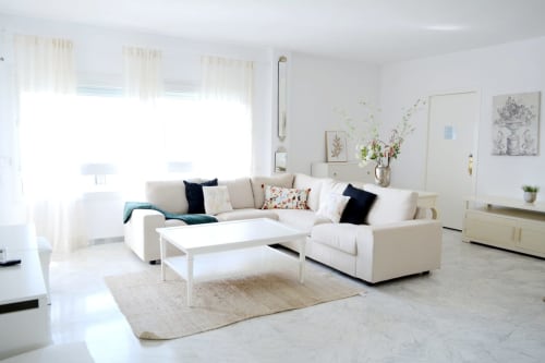 Bright, modern living room at Royal Banus Marbella with cream sectional sofa, white coffee table, beige rug, and natural