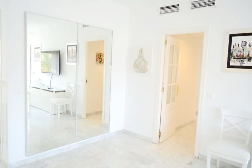 Modern minimalist hallway at Royal Banus Marbella apartment with glass doors and cream-colored walls