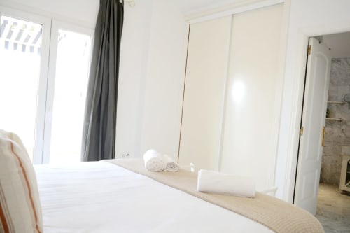 Modern bedroom at Royal Banus Marbella with white bed, mirrored wardrobe, and sliding doors opening to sea-view terrace